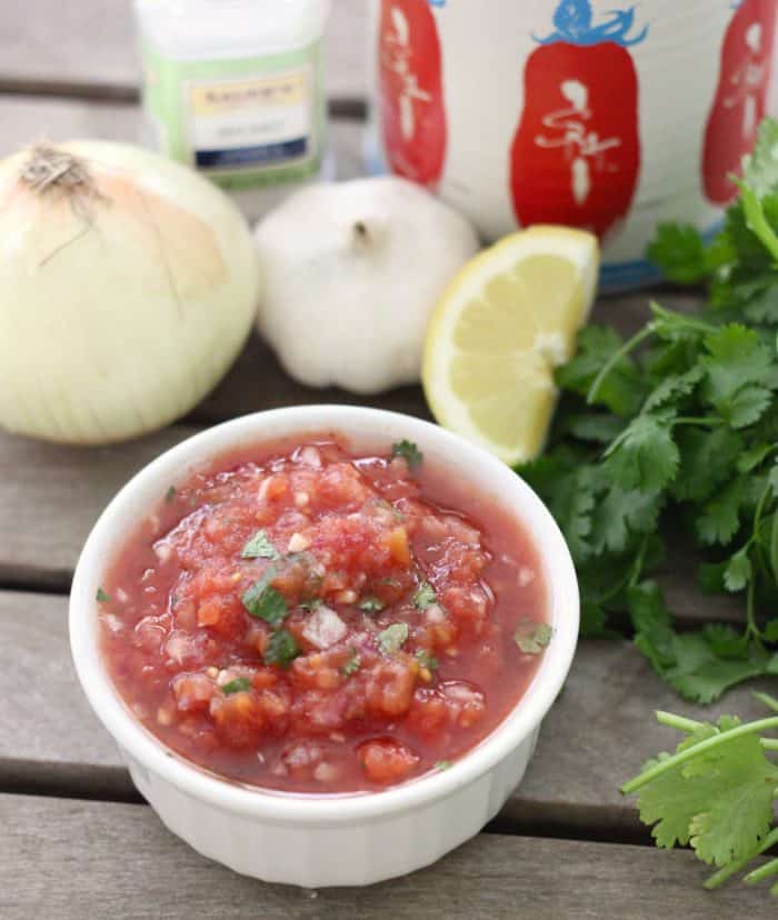 white bowl with homemade salsa, cilantro, lemon slice, garlic, onion, salt, canned tomatoes