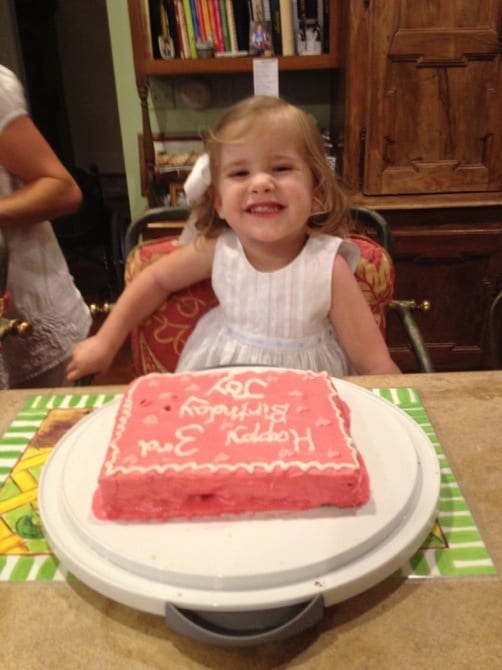 3 year old little girl smiling in front of an allergy-free birthday cake.