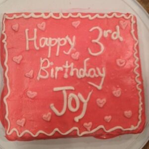 allergy friendly birthday cake that says "happy 3rd birthday Joy" in pink icing.