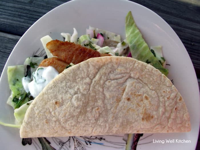 white patterned plate with fish tacos with cabbage slaw and yogurt sauce