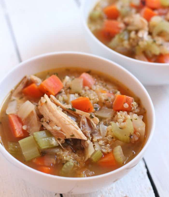 two white bowls of turkey quinoa soup on white wooden table