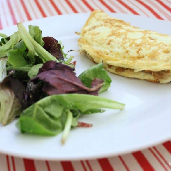 white and red tablecloth with a white plate that has a salad and an omelet.