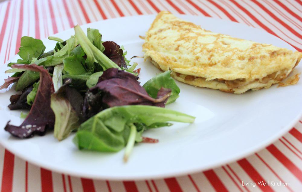 white and red tablecloth with a white plate that has a salad and an omelet.