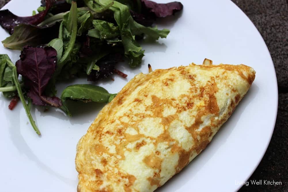 white plate with salad and a caramelized onion omelette.