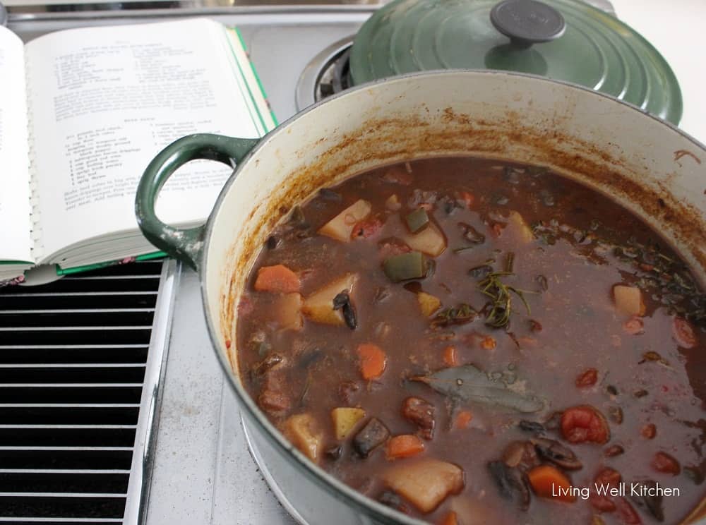 cookbook and pot of beef stew on stove