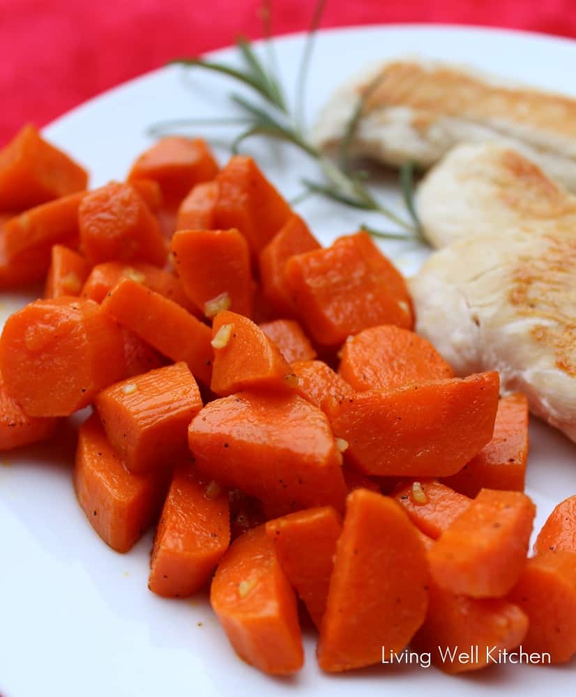 chopped carrots on a white plate with cooked chicken and rosemary