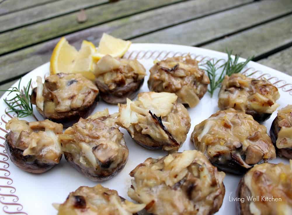 white plate with crab stuffed mushrooms, lemon slices, and fresh rosemary.