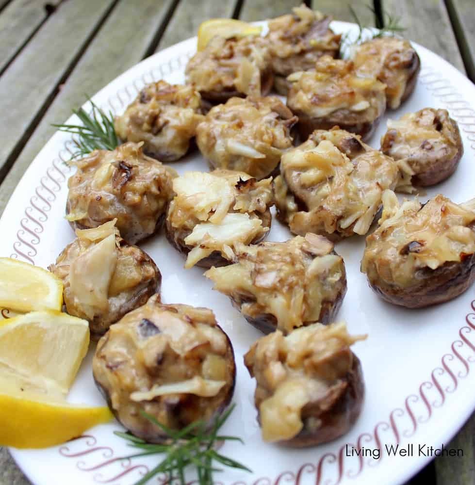 brie and crab stuffed mushrooms, lemon slices, and fresh rosemary on a white plate.