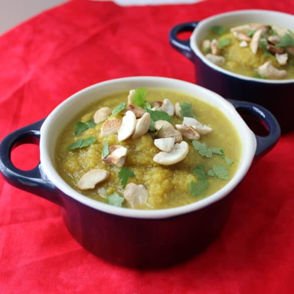 two bowls of Roasted Cauliflower Soup in blue bowls on a red placemat