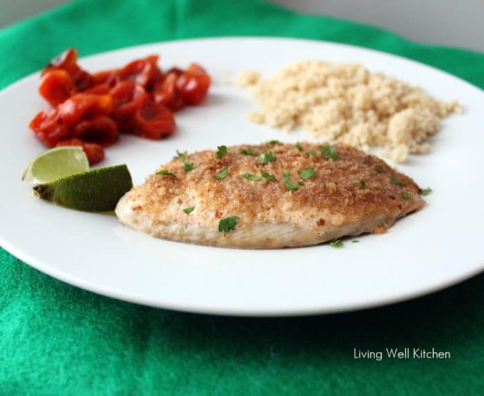 white plate with Easy Baked Fish, lime slice, couscous, and roasted tomatoes