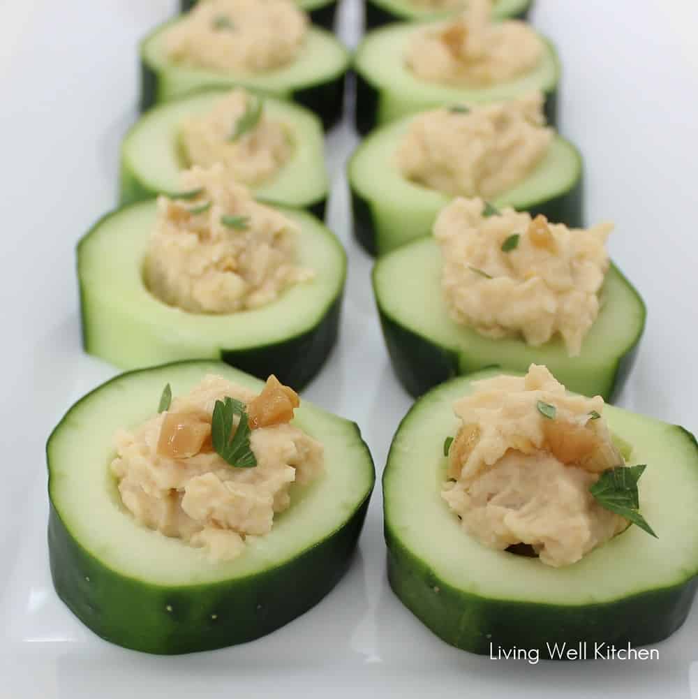 a line of cucumber slices filled with roasted garlic hummus without tahini.