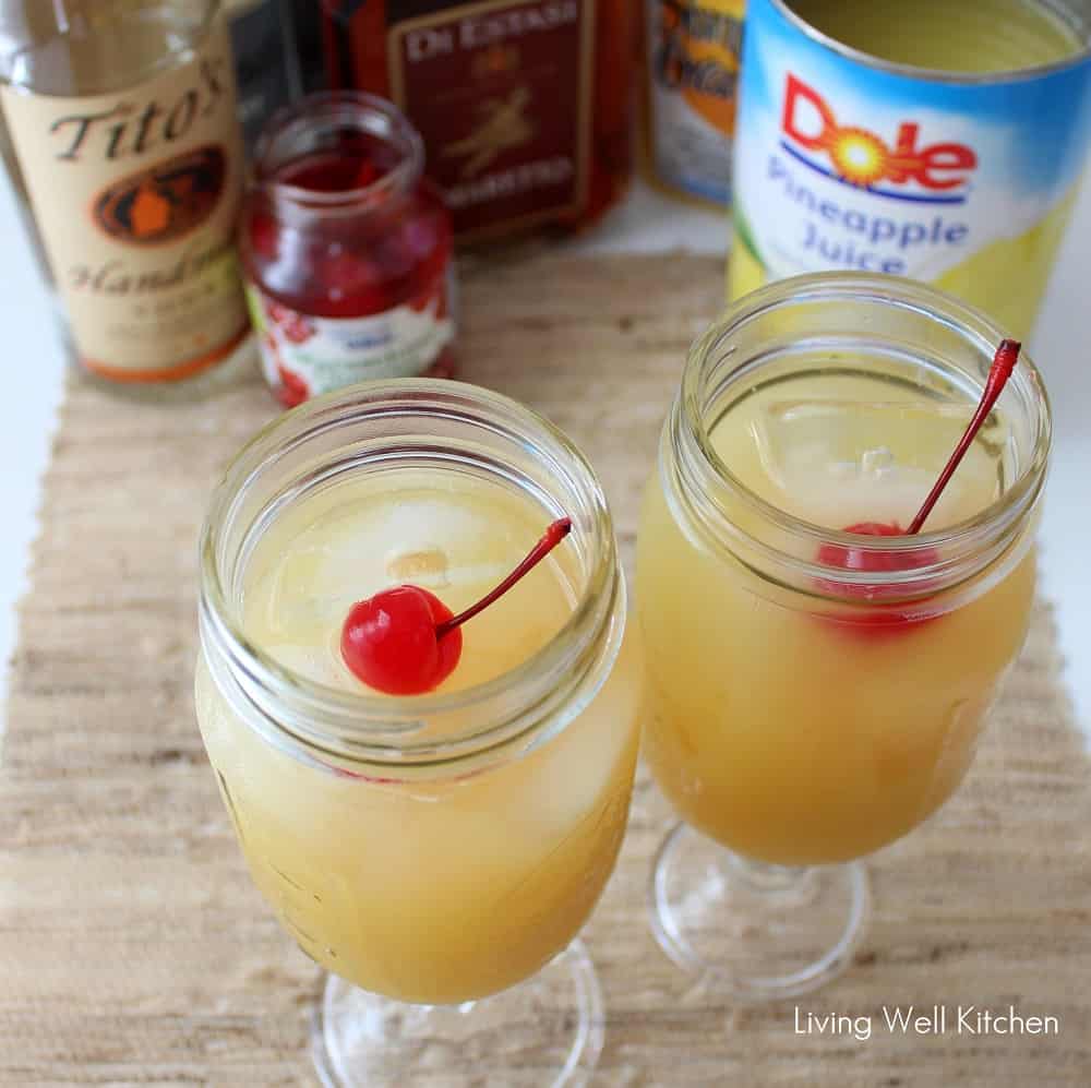 yellow hammer drinks in mason jars with cherries on top, pineapple juice, vodka, cherries