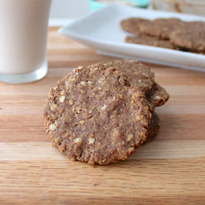 Almond Butter Banana Cookies angled on a stack of cookies with a glass of milk on a wooden table