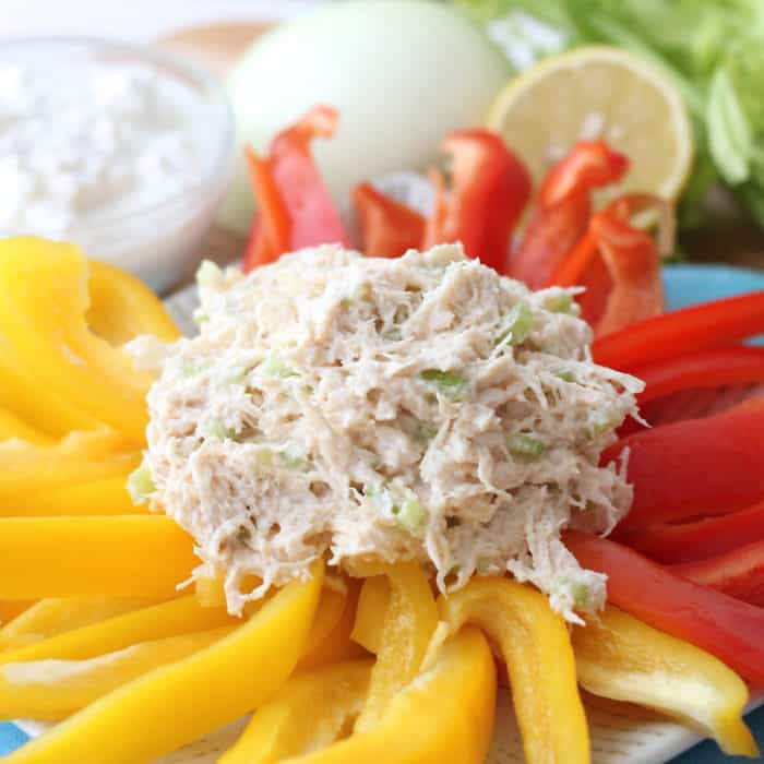 scoop of chicken salad on yellow and red bell peppers with onion, lemon cottage cheese and celery in background