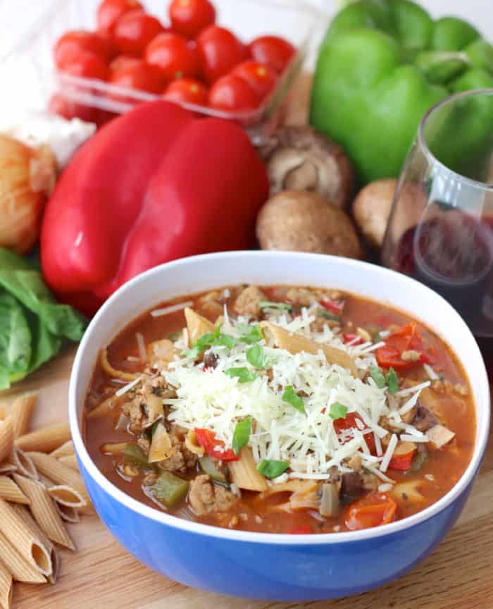 bowl of Pizza Pasta Soup with pasta, peppers, basil, tomatoes, mushrooms, basil and parmesan