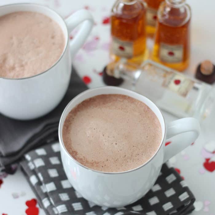 two white mugs of hot chocolate with bourbon and Valentine's confetti 