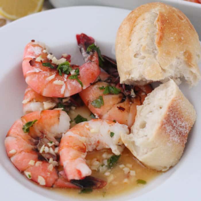 unpeeled shrimp covered in garlic, parsley and butter with french bread