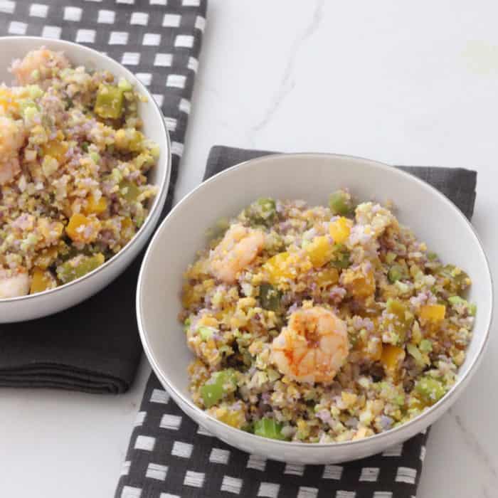 two bowls of Mardi Gras Fried Cauliflower Rice on top of white counter with slate colored napkins