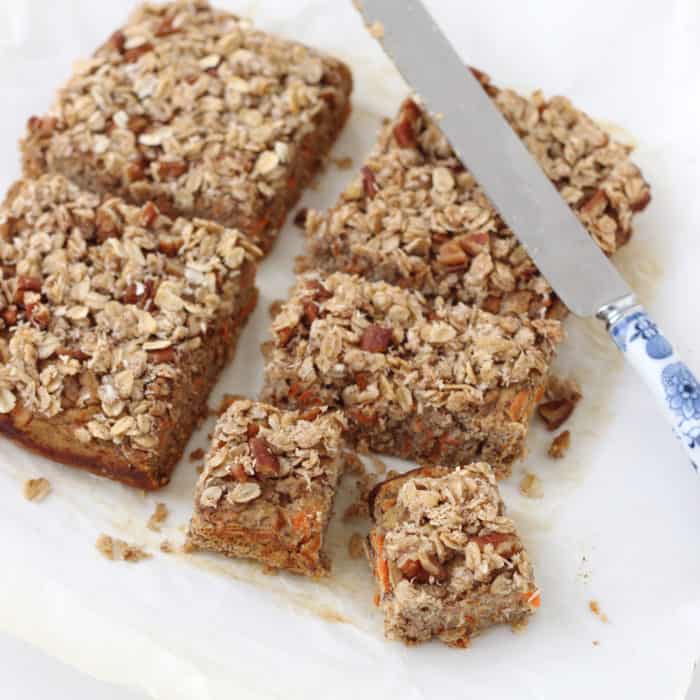 Coconut Carrot Coffee Cake with crumb topping cut into squares on parchment paper with knife