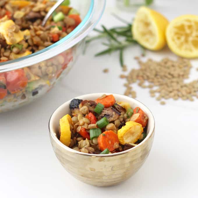 small cup of Roasted Vegetable Lentil Salad with big bowl of salad, lentils, lemons, and rosemary