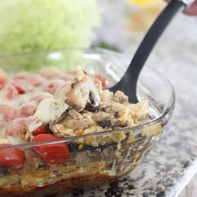 spoon scooping out Veggie and Swiss Breakfast Casserole with mushrooms and tomatoes