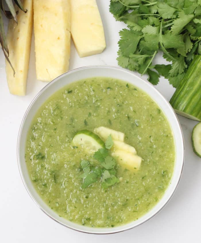 fresh pineapple, cilantro, cucumbers next to a bowl of pineapple gazpacho