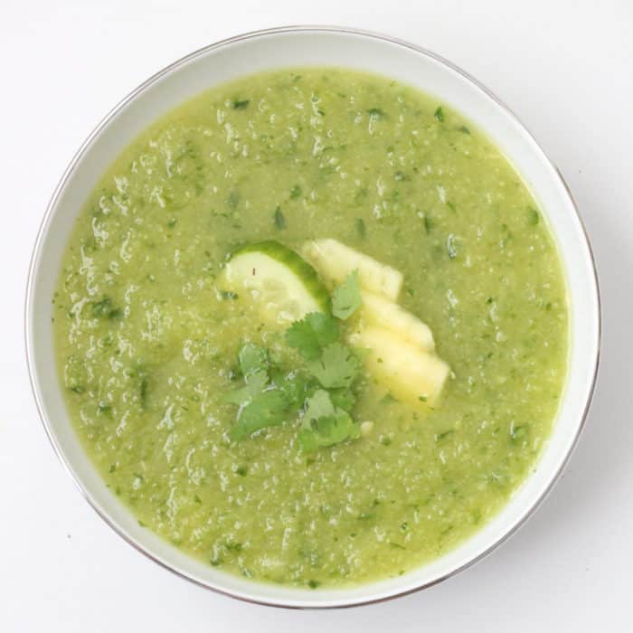 white bowl of Pineapple Cucumber Gazpacho topped with fresh pineapple, cilantro and cucumber