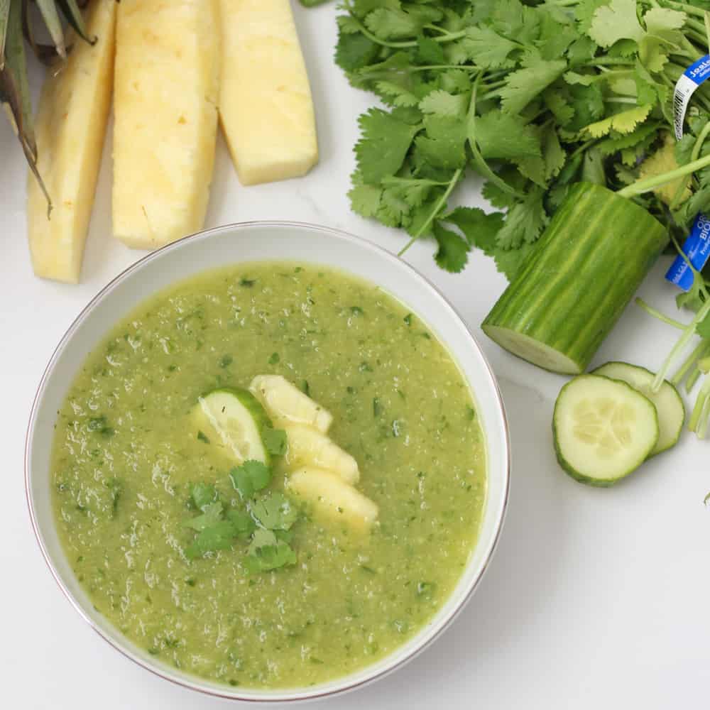 Pineapple Cucumber Gazpacho in a white bowl with fresh pineapple, cilantro and cucumber