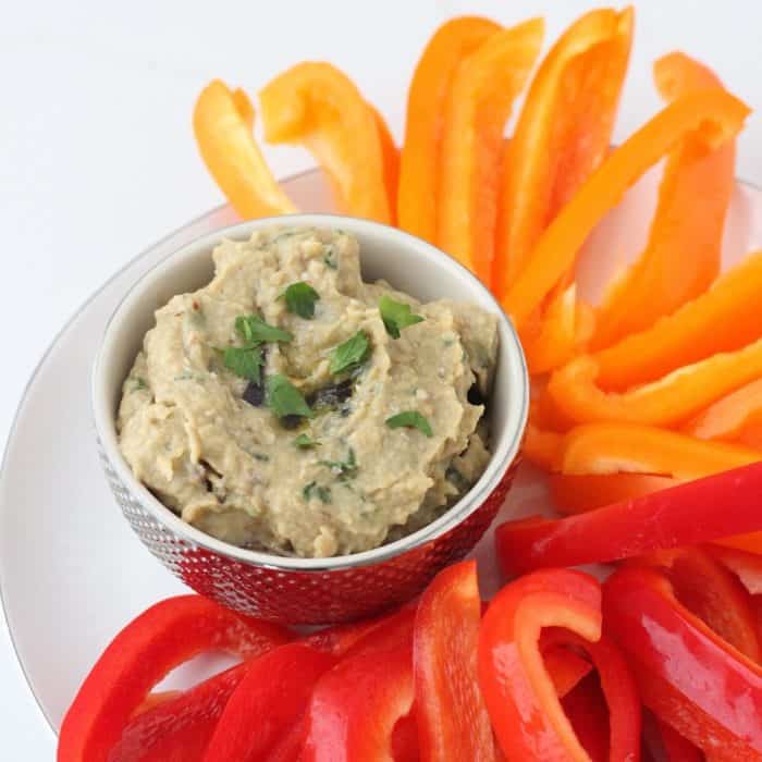 plate of sliced orange and red bell peppers, bowl of eggplant hummus