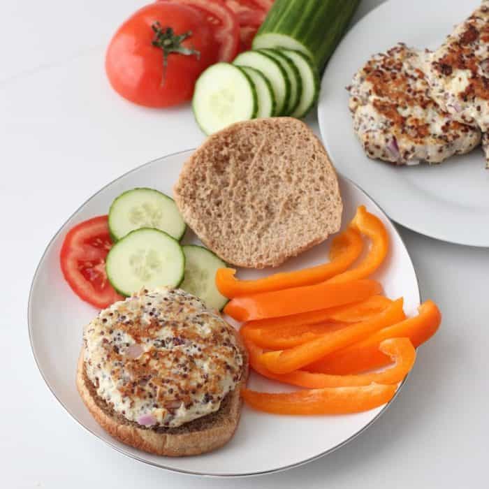 plate of Greek Turkey Quinoa Burgers with bun, cucumber, tomatoes, bell peppers