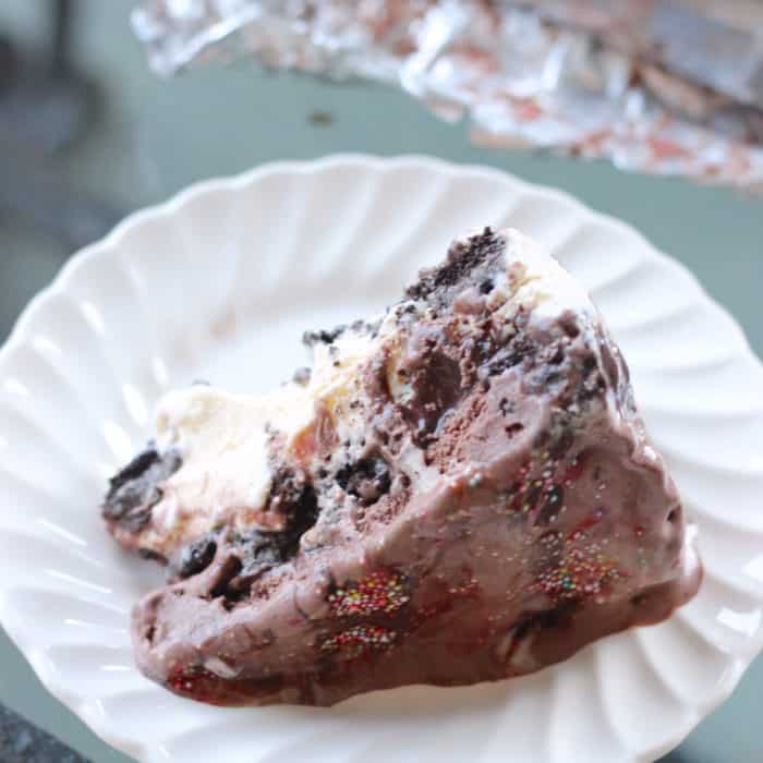 slice of ice cream pie on a white scalloped plate and glass table