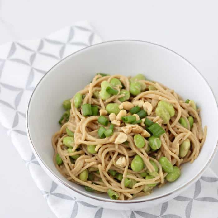 bowl of peanut pasta made in the microwave in a white bowl on a silver and white napkin