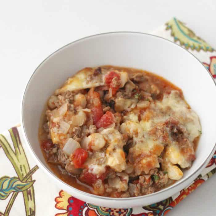 white bowl of hominy casserole on a patterned napkin on a white table