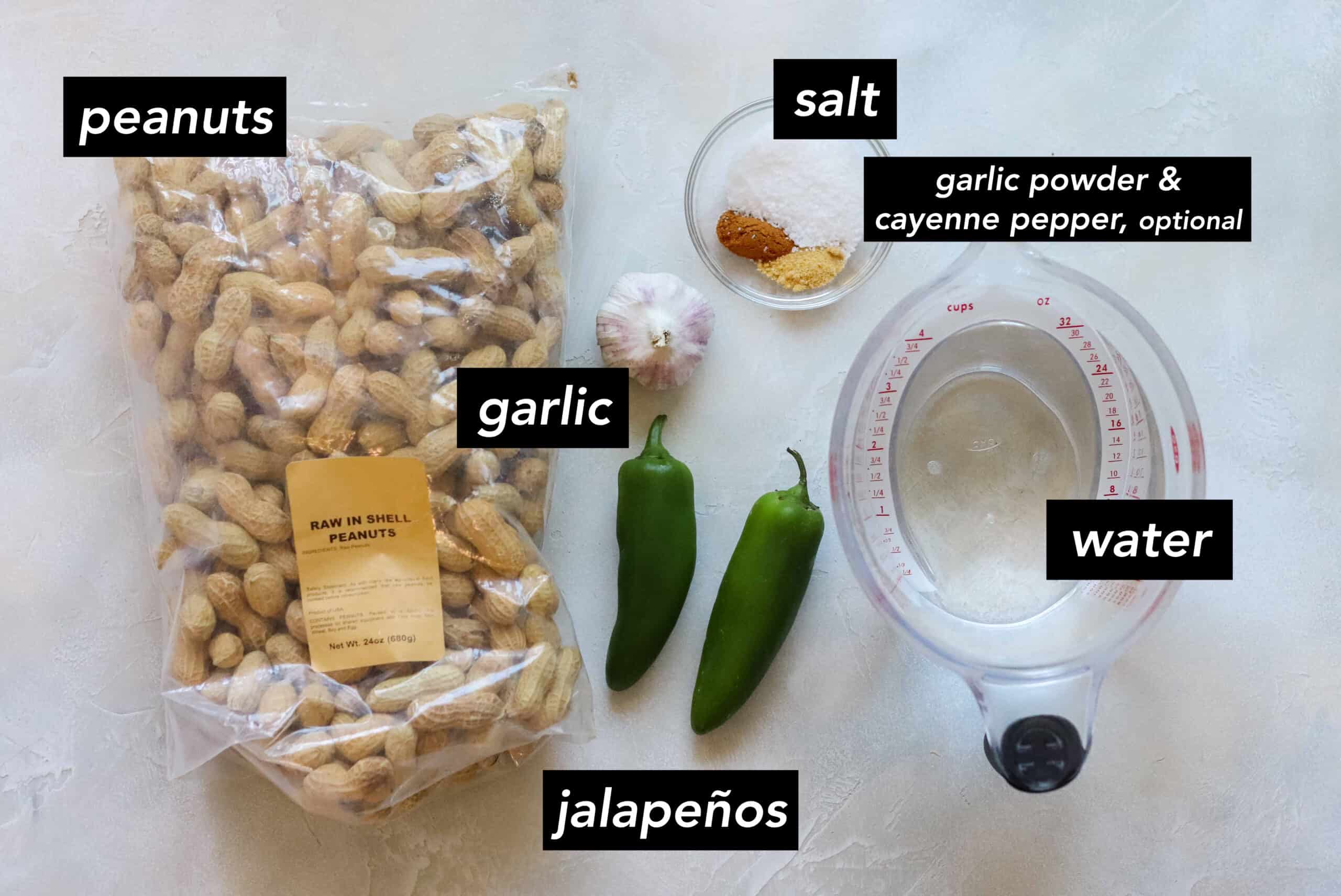 bag of in shell peanuts, head of garlic, two jalapenos, bowl of salt, cayenne pepper, measuring cup full of water