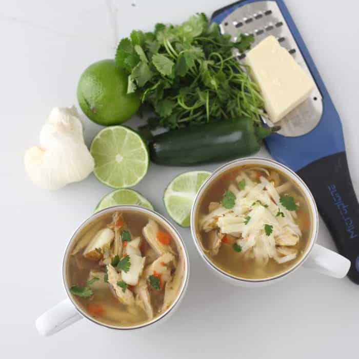 cups of Jalapeño Chicken Soup with cheese, cilantro, limes, and garlic