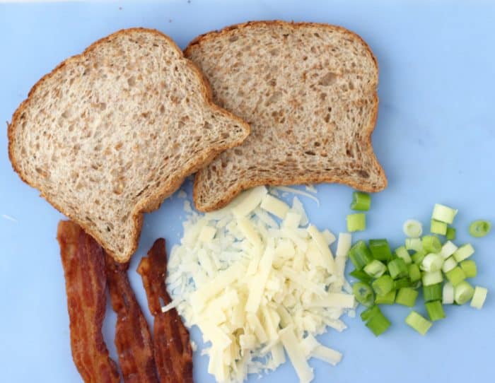 bacon, bread, cheese, green onions on blue cutting board