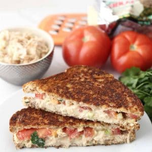 Chicken Salad Grilled Cheese on white plate with tomatoes, chicken salad, cheese grater, parsley