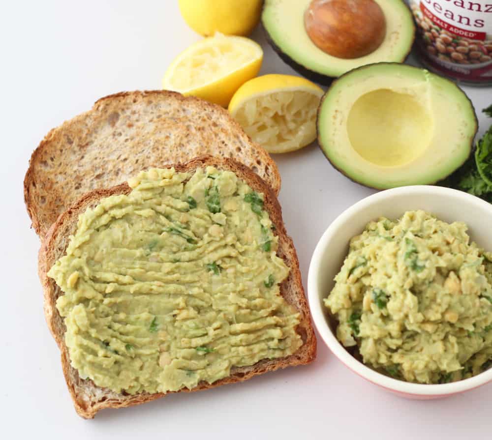 two slices of toast with mashed chickpeas and avocado, bowl of mashed avocado, cut open avocados and lemons
