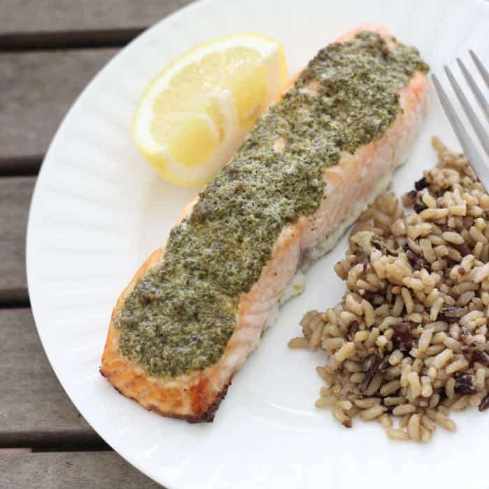 lemon slice, Pesto covered Salmon, wild rice, fork on white plate