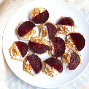 plate of Roasted Beet and Goat Cheese Crackers with walnuts on blue and cream towel