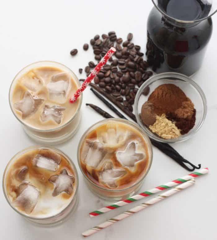 3 glasses with iced Gingerbread Coffee, Christmas straws, vanilla and coffee beans, spices