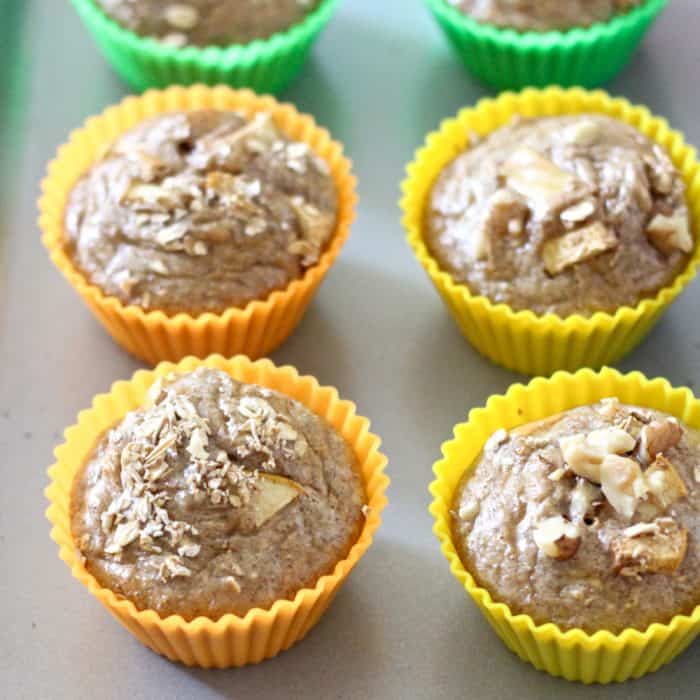 baking sheet with cooked apple protein pancake muffins in orange, yellow and green baking liners