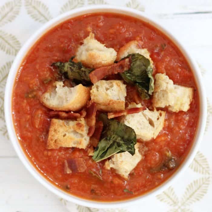 overhead bowl of tomato bread soup with crispy basil, croutons, and bacon