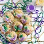mini king cakes on clear plate with green, purple, yellow beads and colored sugar