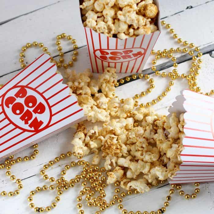 popcorn containers with vegan Cheesy Taco Popcorn on a background of gold beads