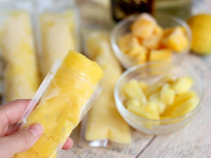 hand holding a Boozy Mango Pineapple Popsicle, frozen pineapple and mango, popsicles