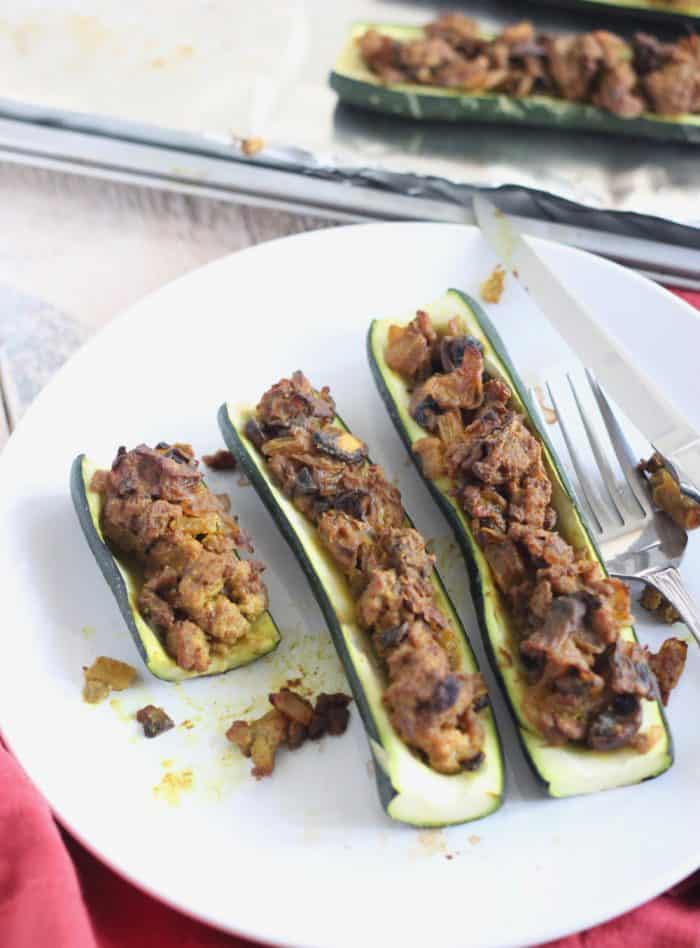 partially eaten Stuffed Zucchini with lamb on white plate, fork and knife