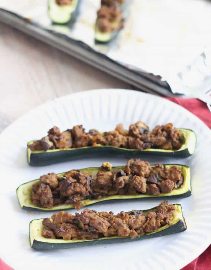 Curry Lamb Stuffed Zucchini on white plate with baking sheet in background