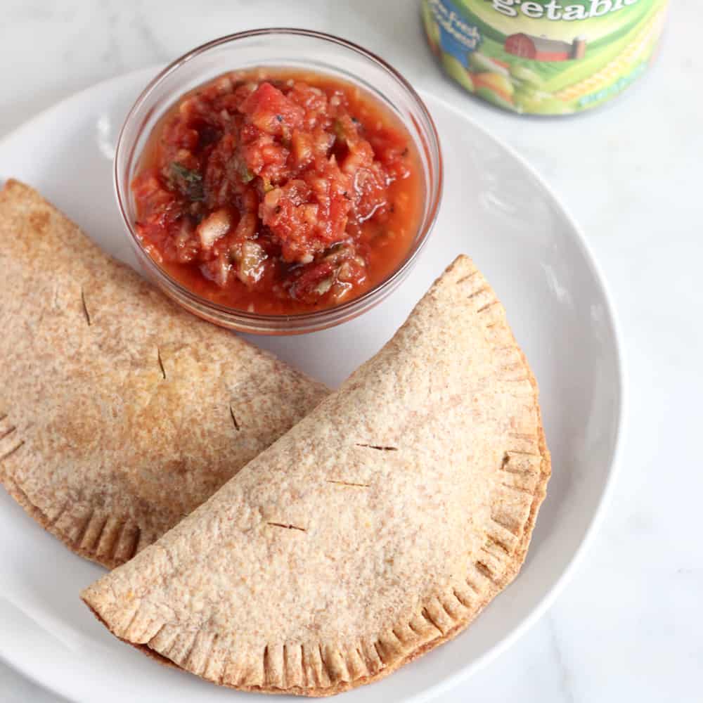 Turkey and Vegetable Empanadas on a white plate with a bowl of salsa next to a can of mixed veggies.