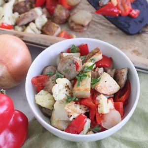 bowl of Roasted Sausage and Veggies with pepper and onion and baking sheet of vegetables